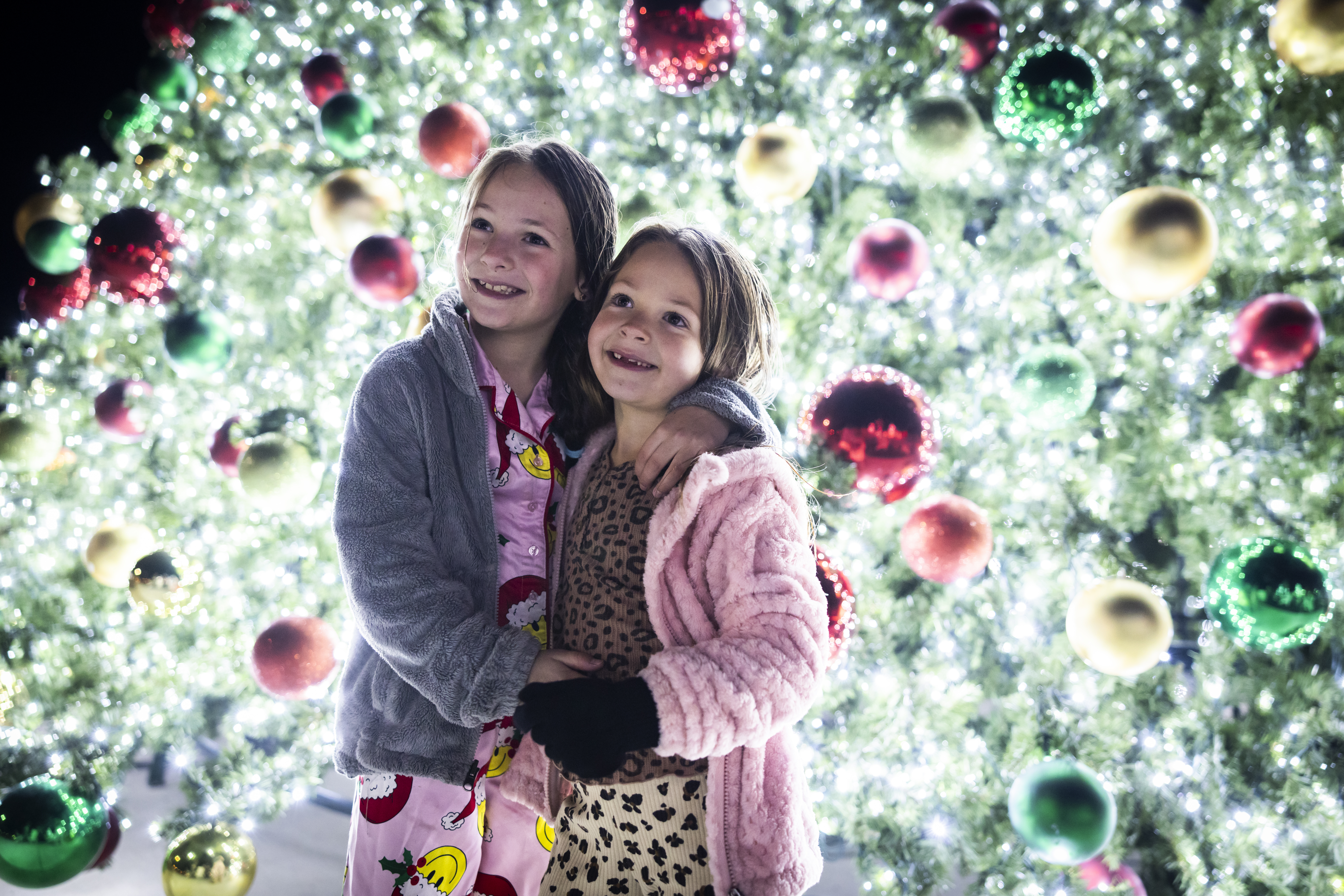 Children enjoy the glow of the Christmas tree decorated with festive lights and ornaments.